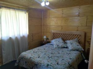 een slaapkamer met een bed met een houten muur bij Cabañas Lomas de Ten Ten in Castro