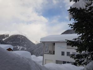 ein schneebedecktes Gebäude mit Bergen im Hintergrund in der Unterkunft Apart Foresta in Samnaun