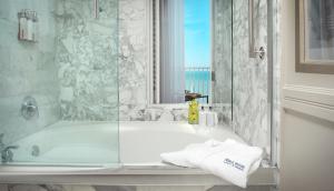 a bathroom with a tub and a glass shower at La Playa Beach & Golf Resort, a Noble House Resort in Naples