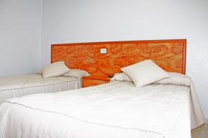 a bedroom with two beds and a wooden headboard at Hotel Trabuco in Santiago de la Ribera