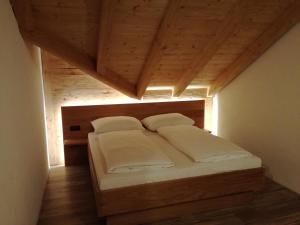 Bett in einem Zimmer mit Holzdecke in der Unterkunft Wieser Hütte in Stockenboi