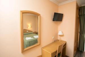 Habitación con cama, espejo y escritorio. en Hotel PAYRO **, en Santiago de Compostela