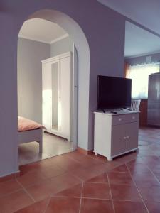 een woonkamer met een tv op een dressoir en een kamer met een deur bij Borókahaus in Tata