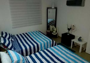 1 dormitorio con 2 camas con rayas azules y blancas en Apartamento con Piscina En el Rodadero Santa Marta Colombia, en Santa Marta
