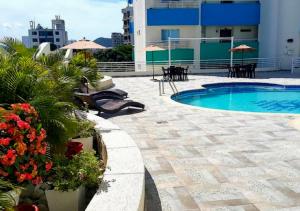 un patio con piscina, mesas y sombrillas en Apartamento con Piscina En el Rodadero Santa Marta Colombia, en Santa Marta