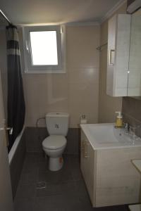 een badkamer met een toilet, een wastafel en een raam bij APARTMENT ALEXANDRA in Nafplio