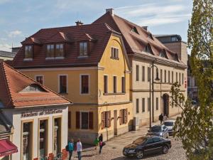 a yellow building with a brown roof on a street at Bed and Breakfast am Schillerplatz in Dresden