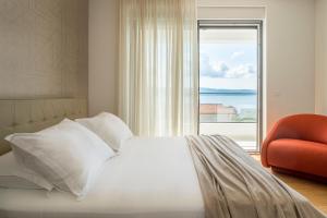 a bedroom with a bed and a chair and a window at Villa Olive Grove in Duće +28 photos