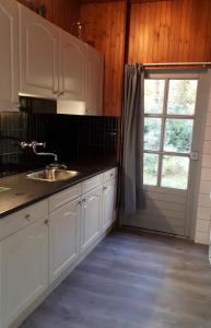 a kitchen with white cabinets and a window and a sink at Bonte Specht in Otterlo