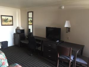 Habitación de hotel con escritorio y TV en Portal Motel, en Lone Pine
