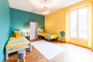 a bedroom with two beds with yellow and blue walls at Newcenter Duplex in Auxerre