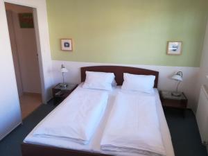 um quarto com uma cama grande com lençóis brancos e almofadas em Apartments Rokytka 308 & 405 em Rokytnice nad Jizerou