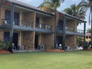an exterior view of a building with a yard at Bribie Waterways Motel in Bongaree