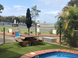 una mesa de picnic con una sombrilla junto a una piscina en Bribie Waterways Motel, en Bongaree