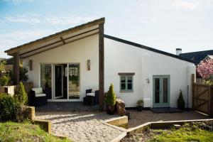 a white house with a porch and a patio at The Burrow at Burrow Wood Farm in Ottery Saint Mary