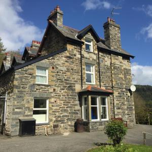 an old stone house with a large window at Woodlands Centre in Betws-y-coed