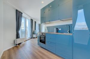 a kitchen with blue cabinets and a large window at City View Apartment 57 in Vilnius
