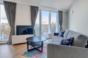 een woonkamer met een bank, een tafel en ramen bij City View Apartment 57 in Vilnius