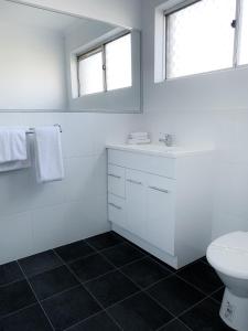 a white bathroom with a toilet and a sink at Cascades Motor Inn in Dubbo