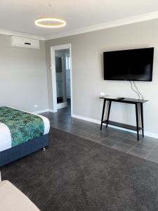 a bedroom with a bed and a flat screen tv at Cascades Motor Inn in Dubbo