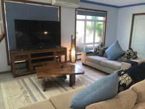 uma sala de estar com uma televisão, um sofá e uma mesa em Taj on Byrnes - Private Luxury Apartment Mareeba em Mareeba