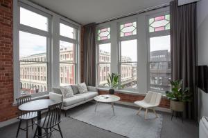 a living room with a couch and chairs and windows at The Chamberson in Dunedin