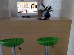 a desk with two green stools and a television at GreenTree Alliance Ningxia Hui Autonomous Region Yinchuan South Bus Station Hotel in Yinchuan