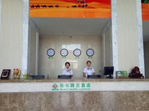 2 personnes assises sur un bureau dans une pièce avec des horloges dans l'établissement GreenTree Alliance Ningxia Hui Autonomous Region Yinchuan South Bus Station Hotel, à Yinchuan