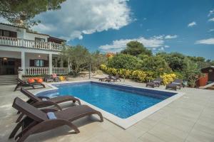 a swimming pool with chairs and a house at Villa Mima in Banjole
