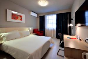 a hotel room with a white bed and a red chair at Jinjiang Inn Chengdu Dianzi Road in Tianhuizhen
