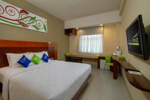 a bedroom with a large bed and a television at PrimeBiz Hotel Kuta in Kuta