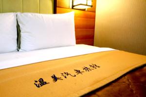 a bed with a white bedspread with a sign on it at Wen Mei Motel in Nantou City