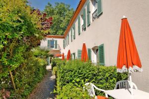 pomarańczowy parasol siedzący obok budynku w obiekcie Best Western L'Orangerie w mieście Nîmes