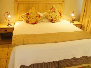 a bedroom with a bed with white sheets and pillows at Villa Jana Guesthouse in Pretoria