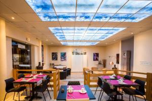 a restaurant with tables and chairs and a sky ceiling at Best Western Hôtel Des Voyageurs in Fougères