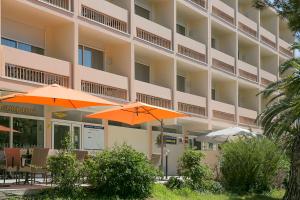 deux parasols oranges devant un hôtel dans l'établissement Best Western Hôtel des Thermes - Balaruc les Bains Sète, à Balaruc-les-Bains