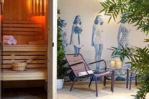 a room with a chair and a wall with drawings of women at Best Western Les Bains Hotel et SPA in Perros-Guirec