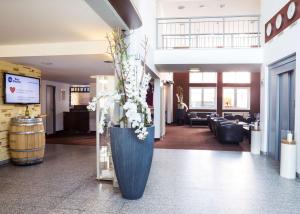 un vestíbulo con un gran jarrón azul con flores en Best Western Hotel München Airport, en Erding