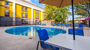 a table with an umbrella next to a swimming pool at Best Western Plus Bloomington East in Bloomington