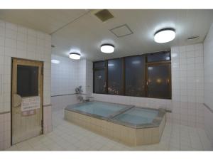 ein Bad mit einer Badewanne in einem Zimmer mit Fenstern in der Unterkunft Famy Inn Makuhari in Chiba