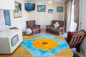 a living room with a table with a sunflower on it at De Helling Self Catering in Brackenfell