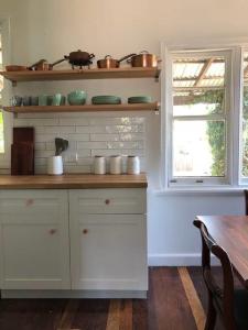 a kitchen with white cabinets and a table and a window at Gallery House Dwellingup in Dwellingup