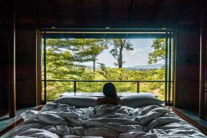 a woman laying in bed looking out a window at Villa Zolitude Resort & Spa - SHA Extra Plus in Chalong