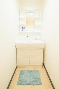 a bathroom with a sink and a mirror and a rug at Secret Base in Sannomiya in Kobe