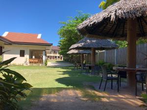 um quintal com mesas, cadeiras e guarda-sóis em Malapascua Starlight Resort em Malapascua