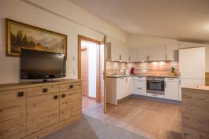 a kitchen with a flat screen tv on a wooden cabinet at Apart Heim in Fügen