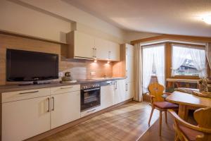 a kitchen with white cabinets and a table and a television at Apart Heim in Fügen