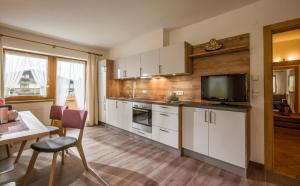 a kitchen with white cabinets and a tv and a table at Apart Heim in Fügen