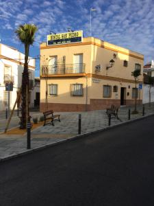 un edificio con due panchine di fronte a una strada di Hostal San Pedro a Sanlúcar la Mayor