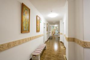 a hallway with a bench and paintings on the walls at Zámek Lužec Spa & Wellness Resort in Karlovy Vary